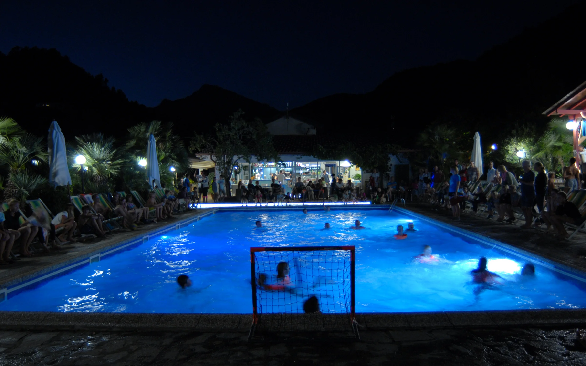 Waterpolo in het verlichte zwembad in de avond
