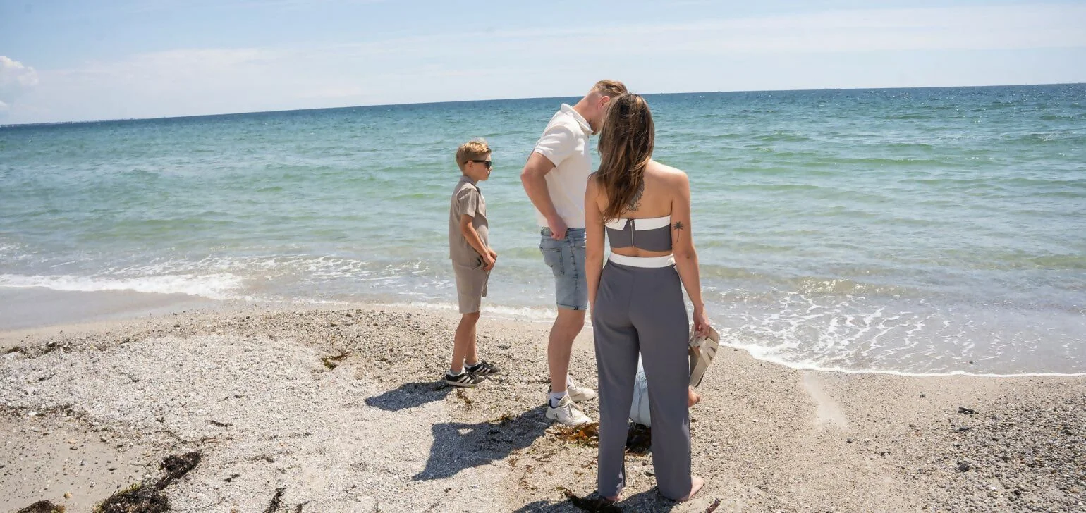 Famiglia in riva al mare su una spiaggia con conchiglie e ciottoli sulla costa bretone