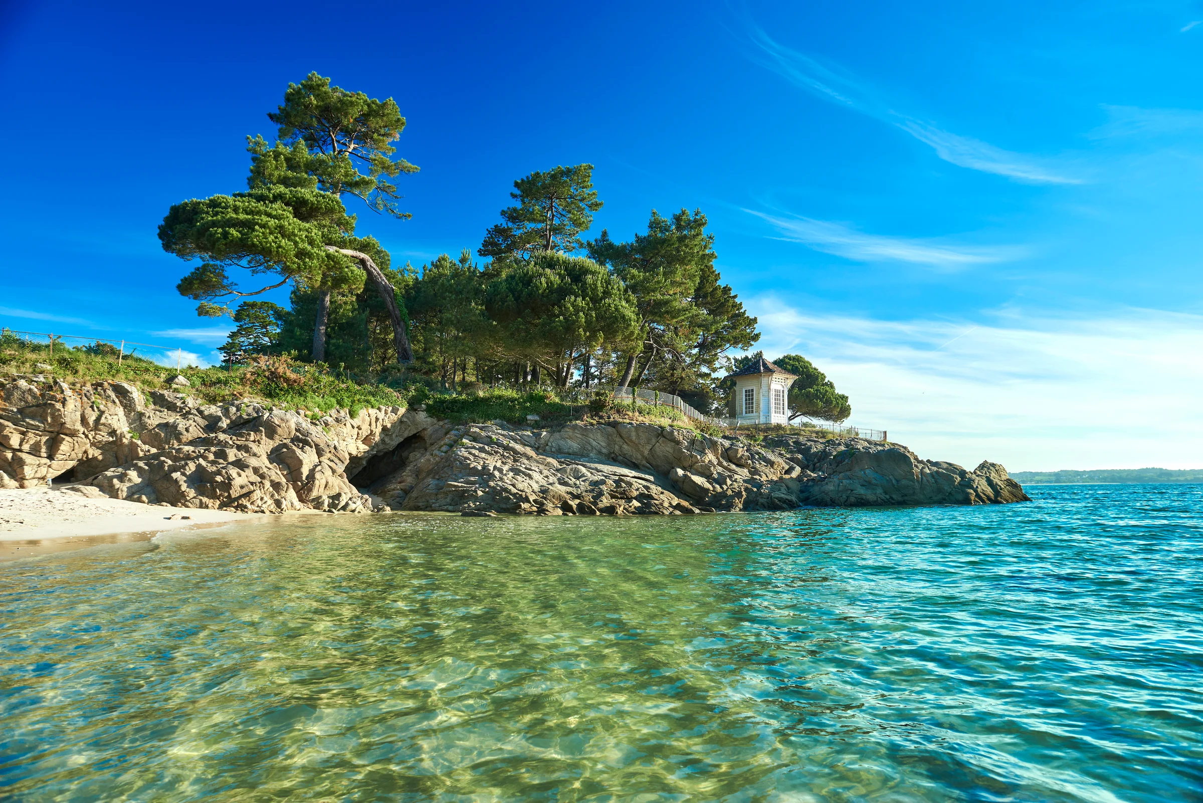 Rotsen met dennen in turquoise water aan de kust van Bretagne
