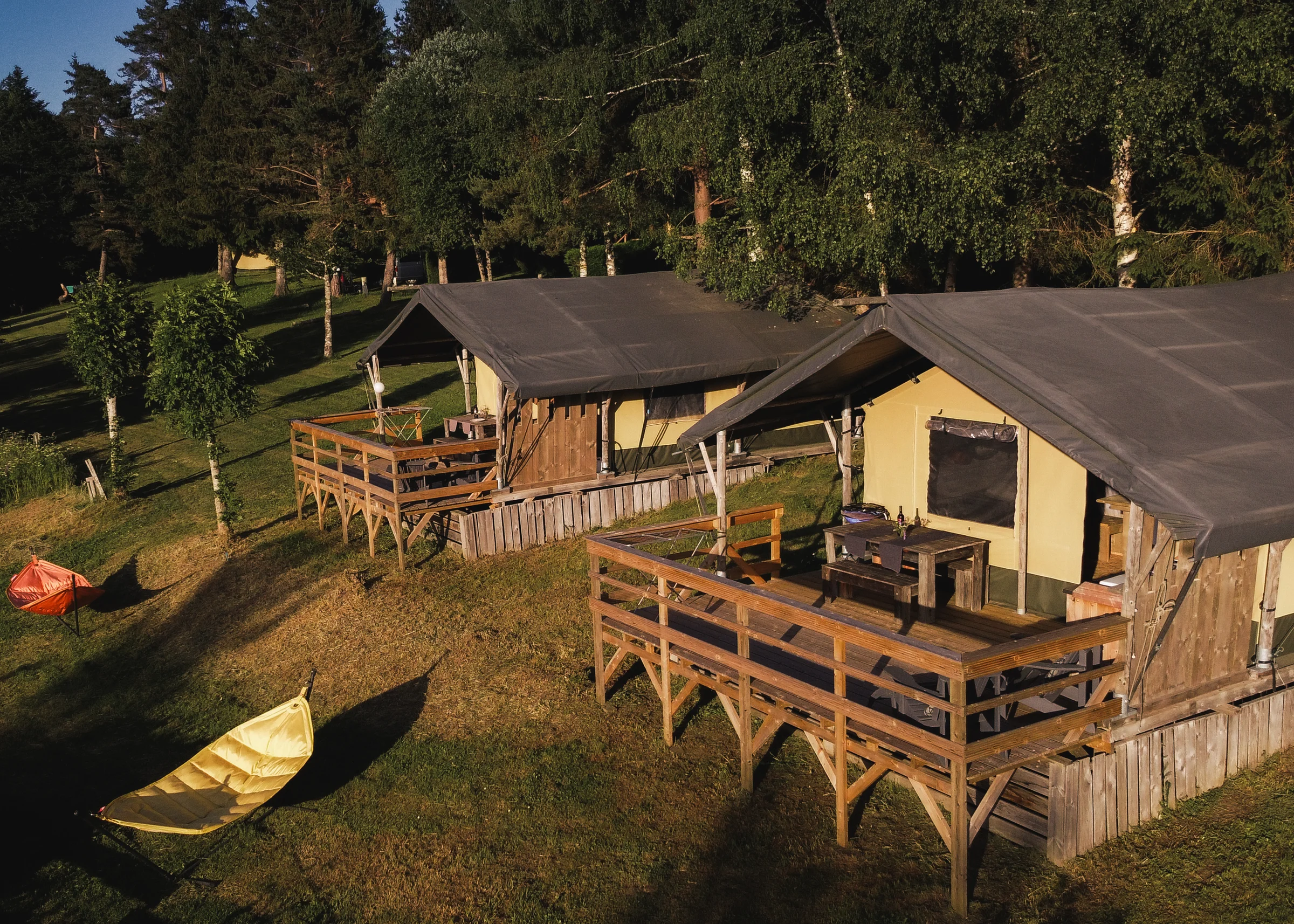 Dva Base Lodgea na stupovima s terasom u večernjem suncu na Les Sapins